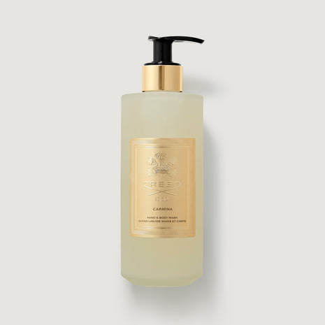 Bottle of Carmina hand and body lotion with a gold label on a light gray background