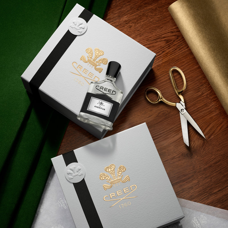 Creed perfume bottle with packaging on a wooden surface